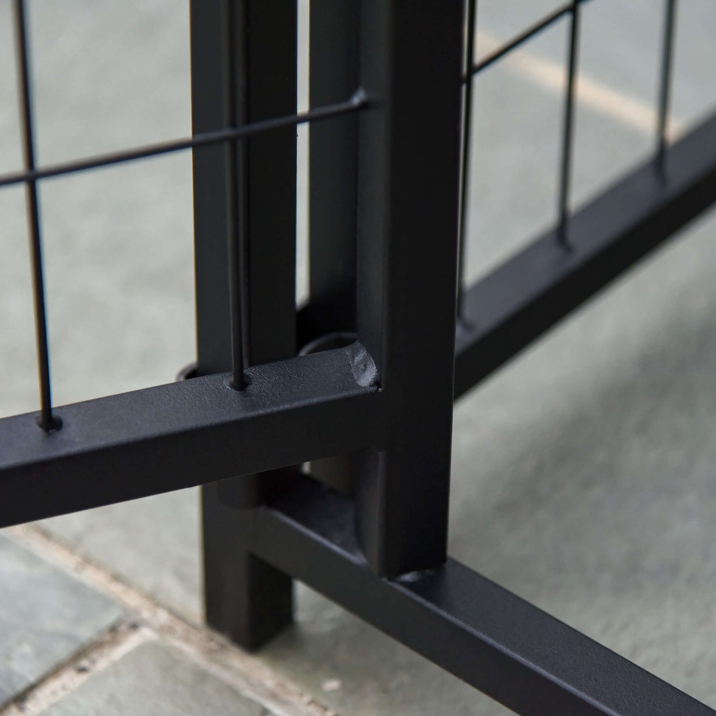 Close-up of the sturdy steel frame and corner connections of a black dog playpen.